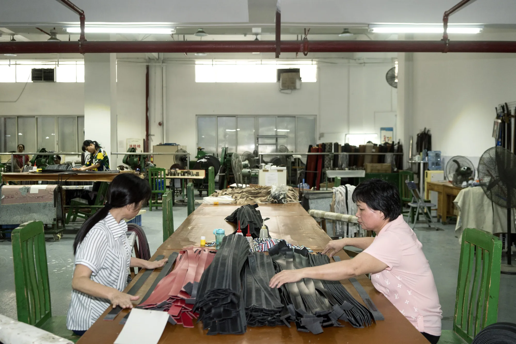 Employees sort through strips of leather to be manufactured into belts at a factory in Guangzhou, China.