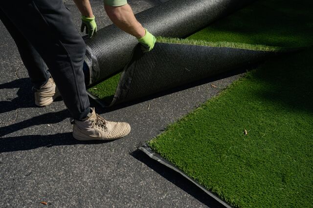 Artificial turf is measured to be installed in the front yard of Judy Dunn's home.