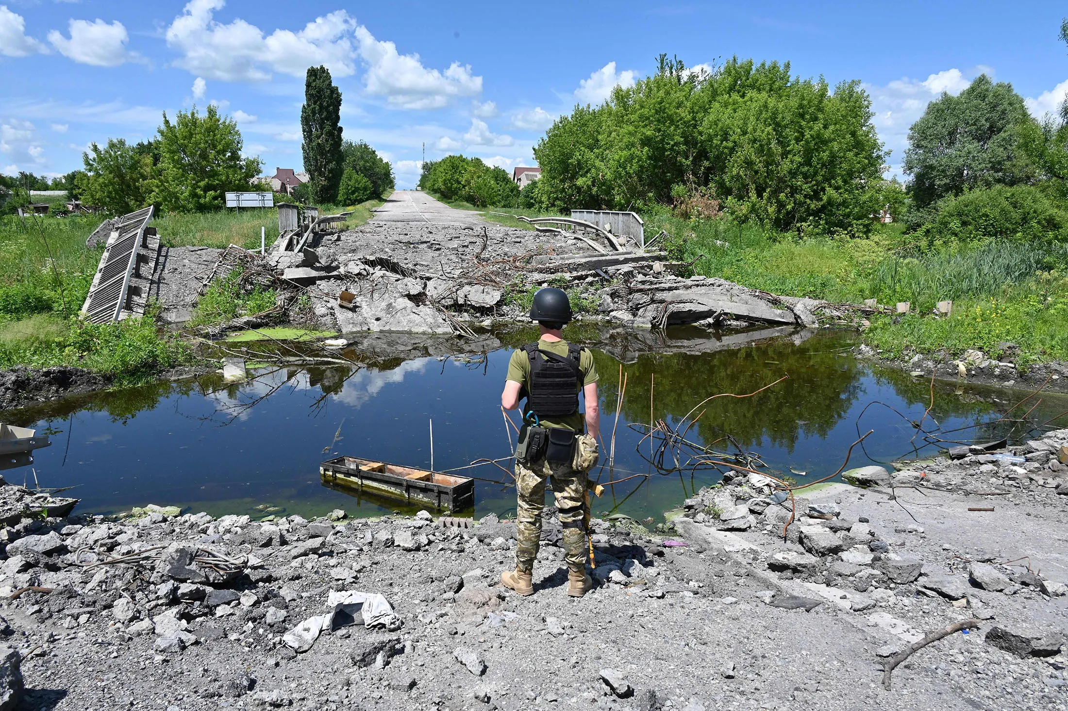A Ukrainian soldier inspects a destroyed bridge over the Lozovenka River near Kharkiv on June 16.