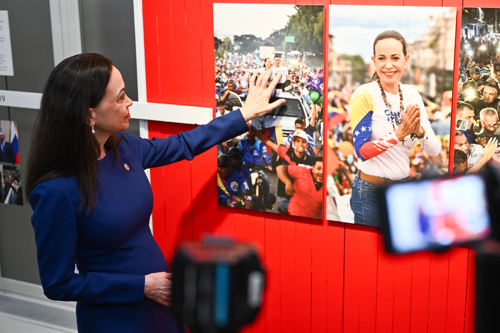 Maria Corina Machado, laureate of the 2025 Nobel Peace Prize, looks at her news photo at the official opening of the Nobel Peace Prize Exhibition 2025 in Oslo, Norway, on Thursday, Dec. 11, 2025. Venezuelan dissident María Corina Machado said she plans to ultimately go back home and disappear from authorities to continue fighting for democracy. Photographer: Naina Helén Jåma/Bloomberg
