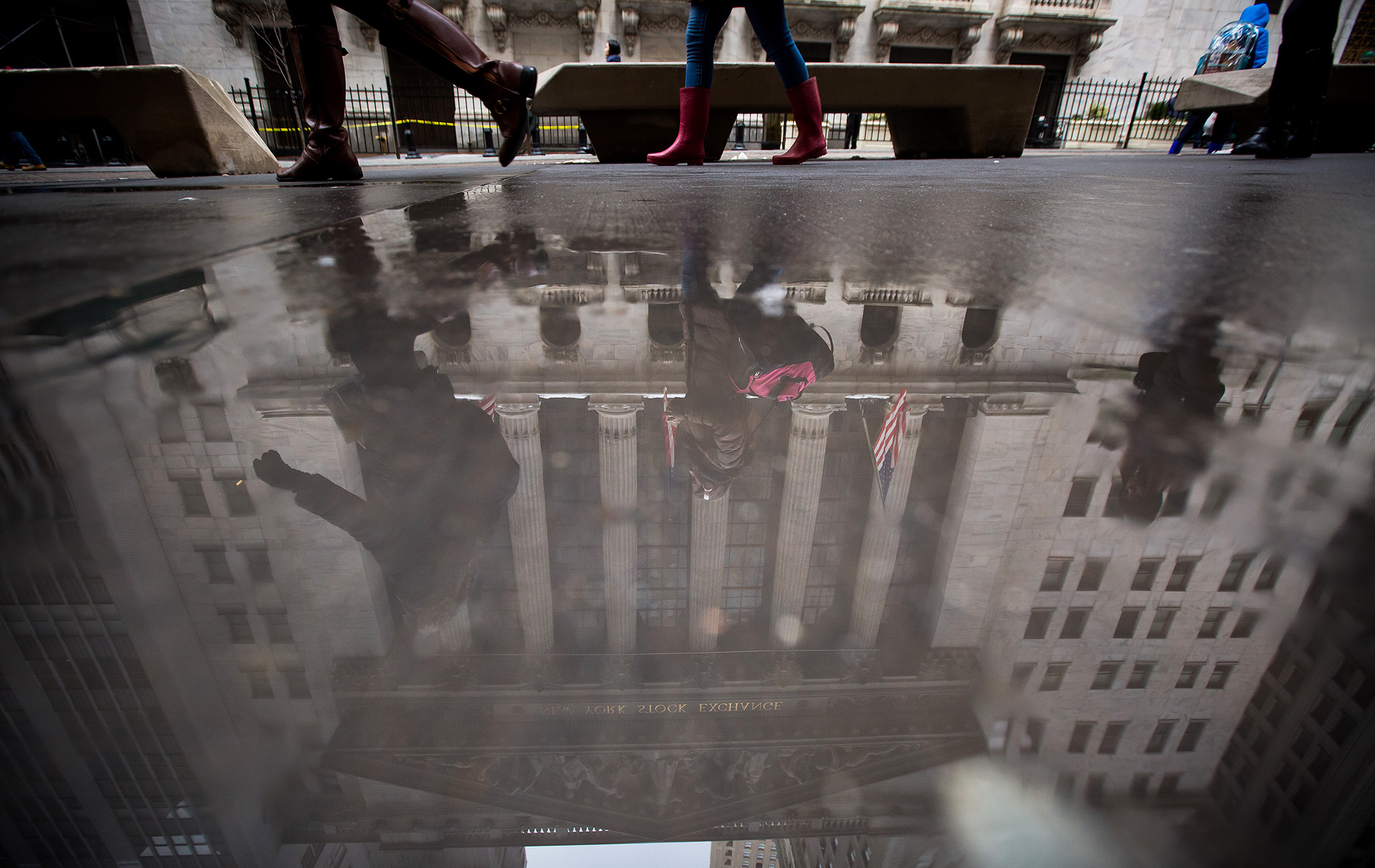 The New York Stock Exchange is reflected in a puddle in New York.
