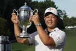 Joohyoung Kim, right, of South Korea, raises the trophy after winning the Wyndham Championship golf tournament in Greensboro, N.C., Sunday, Aug. 7, 2022. (AP Photo/Chuck Burton)
