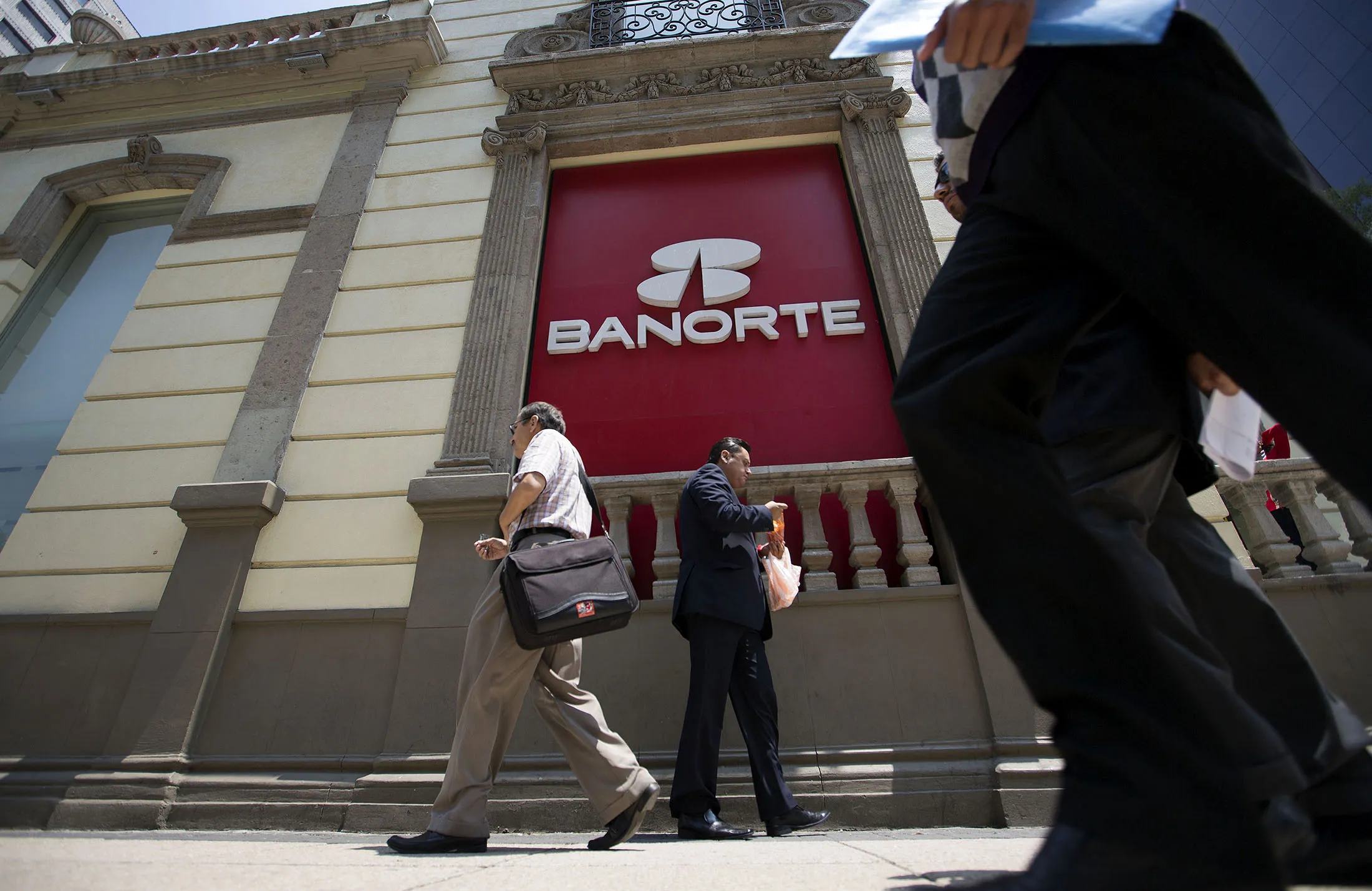 Pedestrians walk past a Banorte SAB bank branch near Reforma Avenue in Mexico City.
