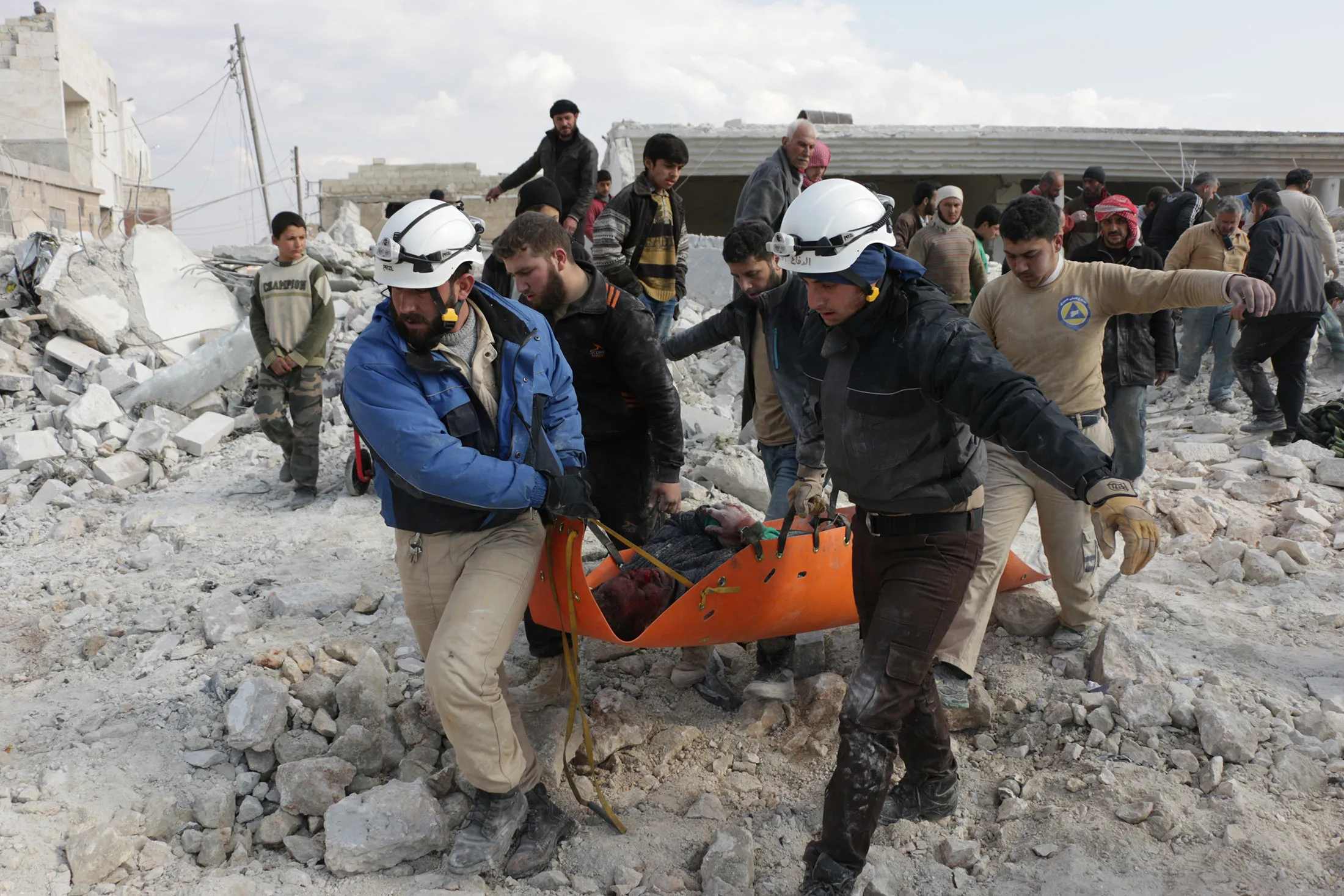 Civil defense team members carry a wounded Syrian on the debris of a building after the war crafts belonging to the Russian army carried out airstrikes on the residential areas in the opposition controlled Anadan district of Aleppo, Syria on Feb. 2, 2016.
