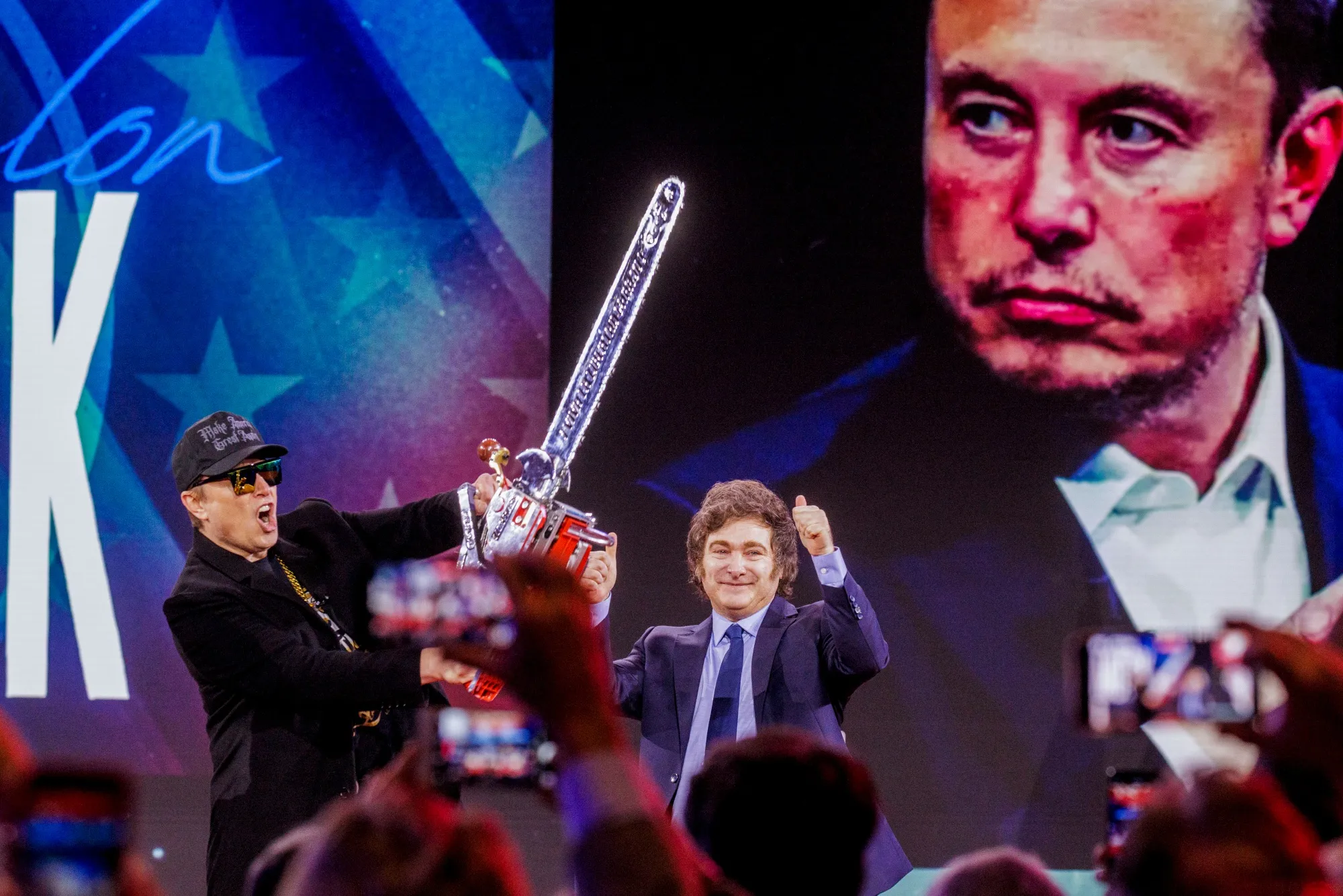 Elon Musk holds a chainsaw gifted to him by Javier Milei during the Conservative Political Action Conference in National Harbor.