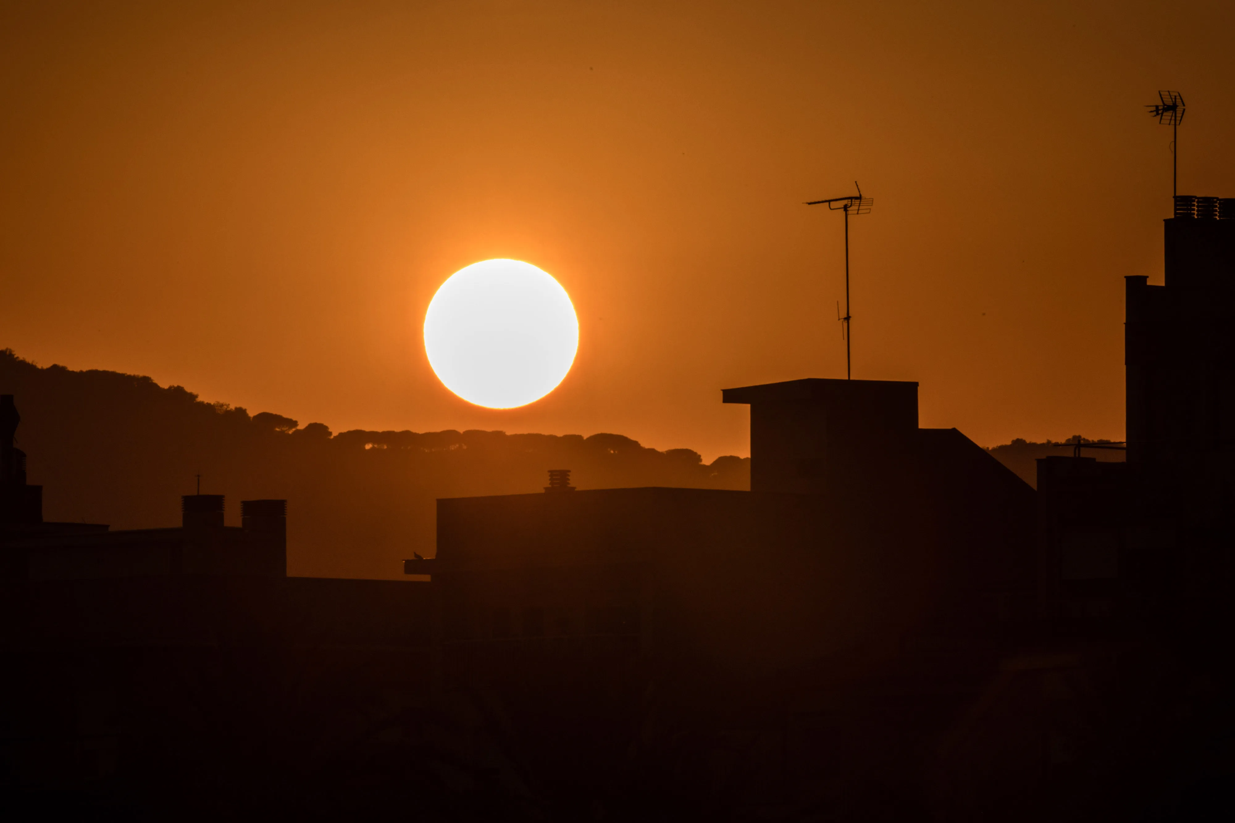 The sun sets beyond residential rooftops in Mataro, Spain, on Aug. 23, 2023.&nbsp;