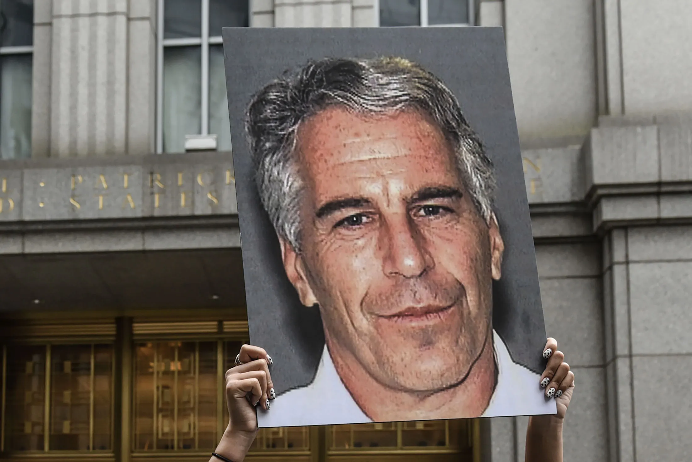 A protester holds a photograph of Jeffrey Epstein outside the federal courthouse in 2019.