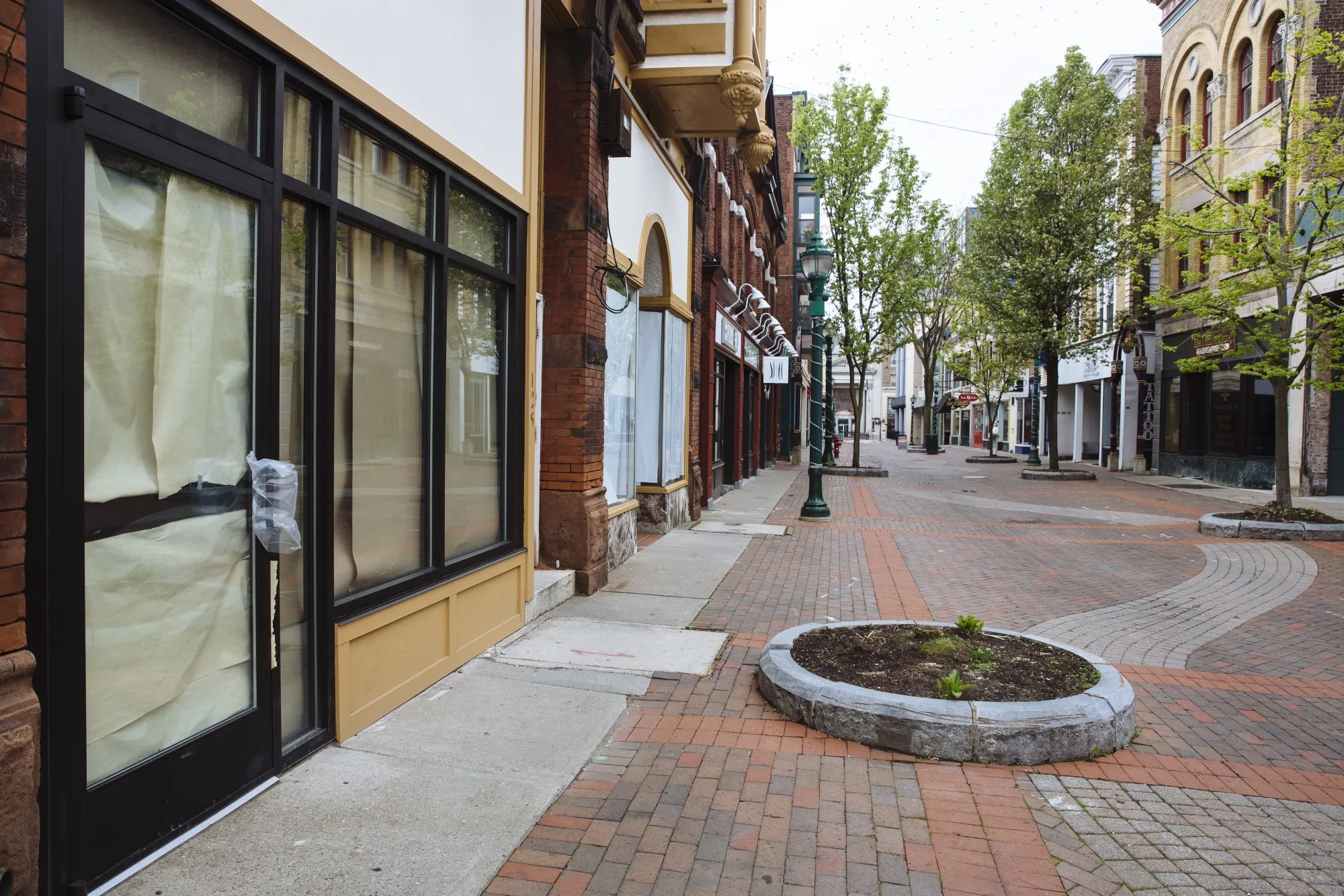 Windows are covered with brown paper at a closed business on an empty pedestrian shopping area in Schenectady, New York, on May 15.