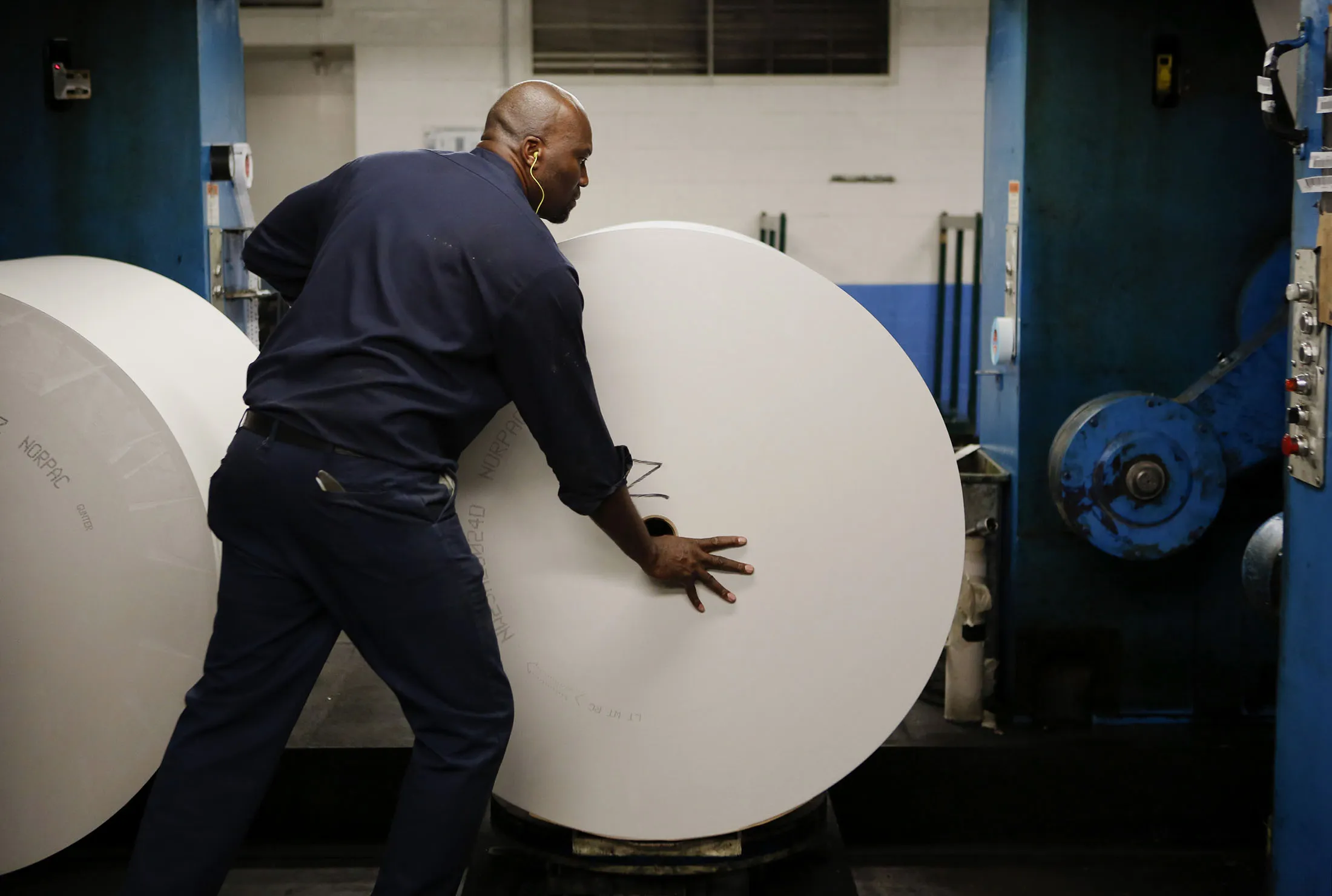 An employee loads a roll of Norpac newsprint at the Los Angeles Times Olympic Press facility in Los Angeles on Oct. 16, 2013.
