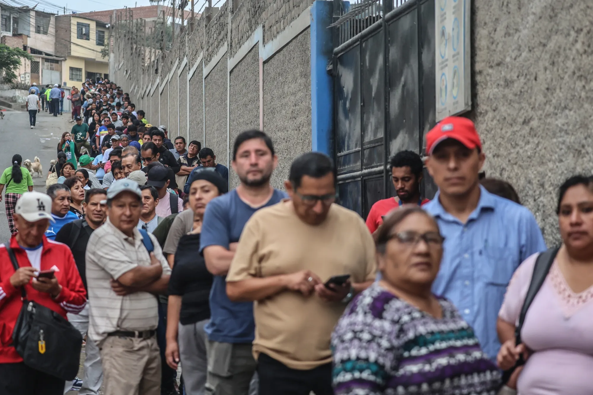 Voters wait in line outside a polling station during the second day of general elections voting in Lima on April 13.