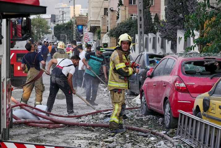 Firefighters and residents clean debris from a site in Tehran, on June 13.