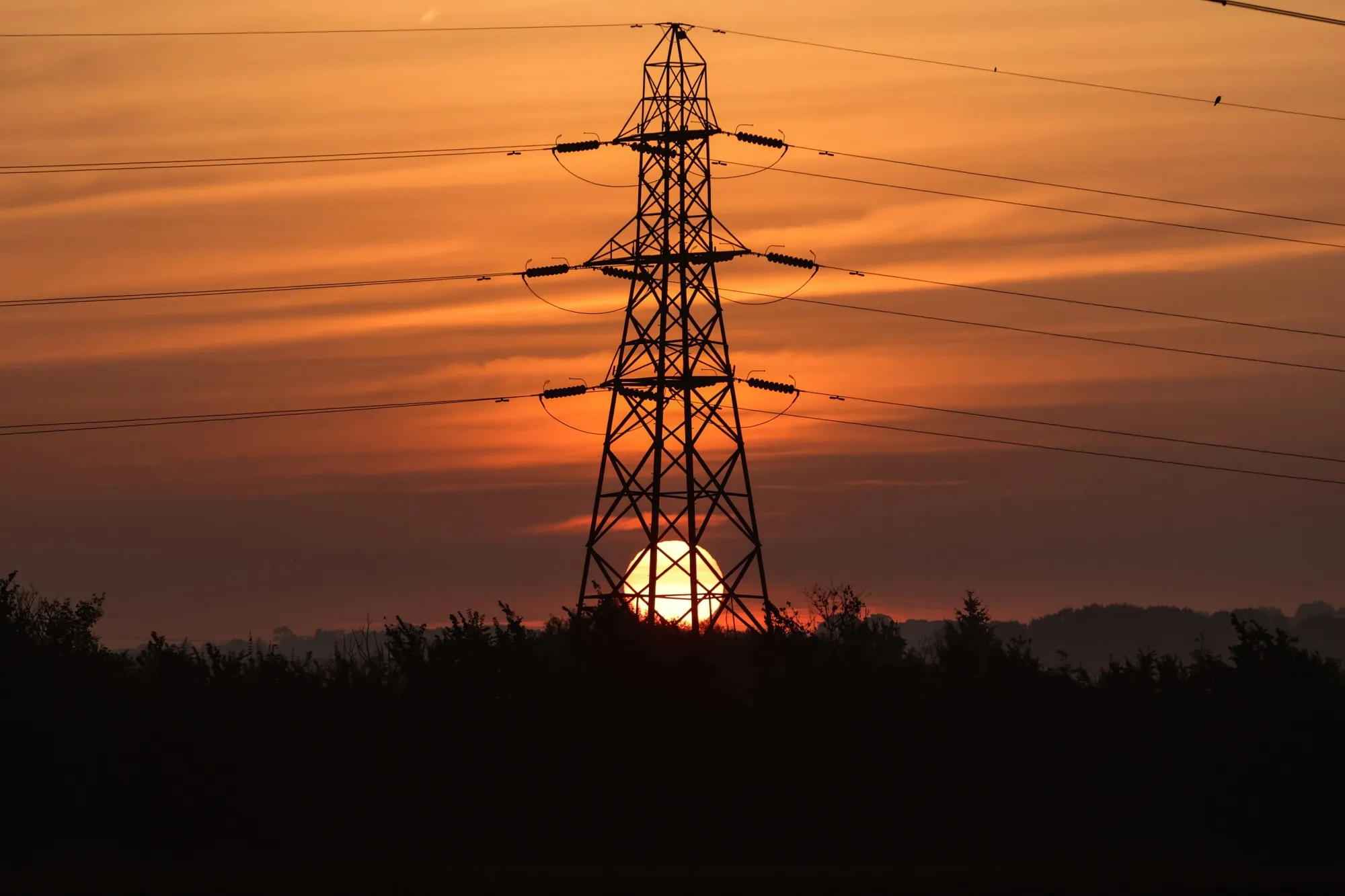An Electricity Pylon In The English Countryside During Sunrise