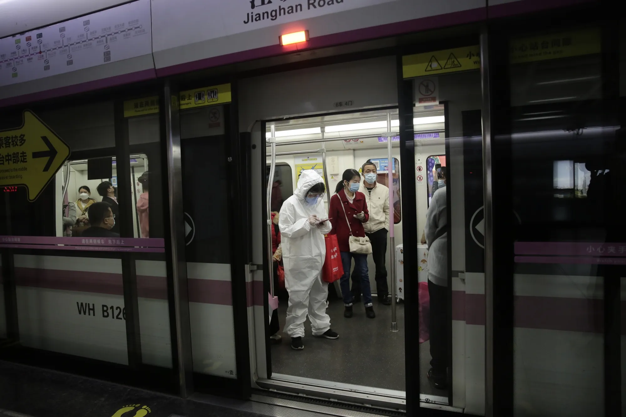 A passenger wearing a protective mask and full-body suit rides in a subway train in Wuhan on April 8.