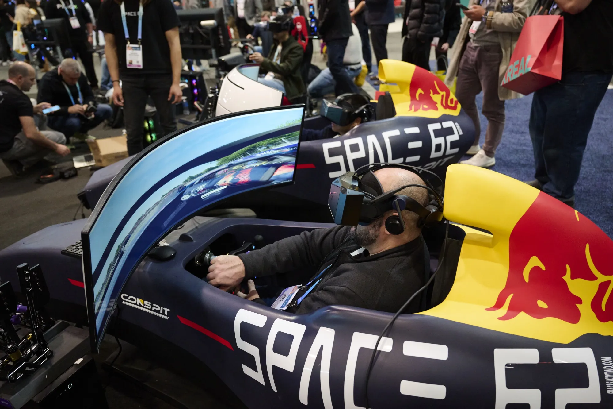 Attendees play a Pimax Formula 1 race simulator during the 2024 CES event in Las Vegas.