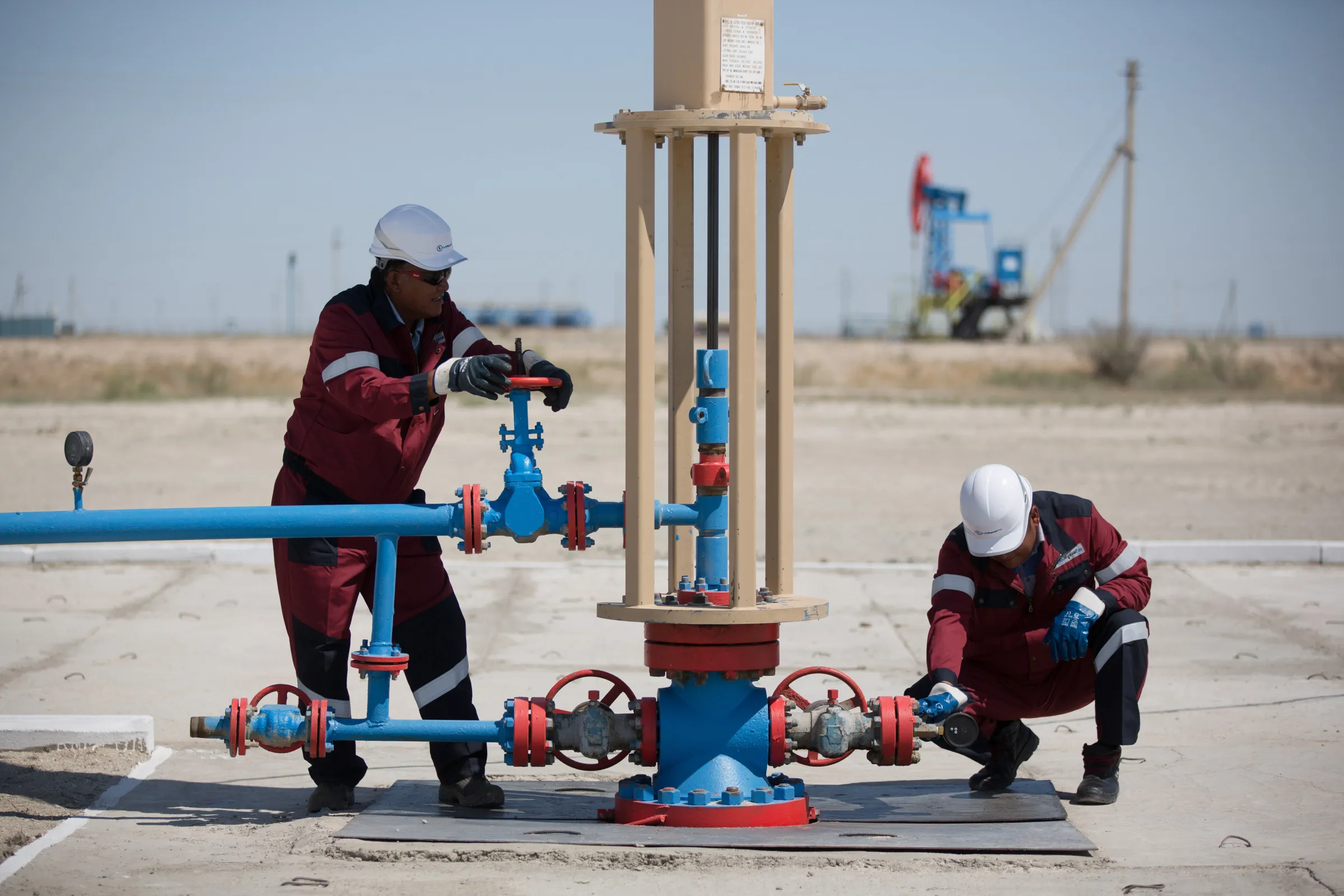 Oil workers adjust flow valves on an oil pumping unit at an oilfield&nbsp;near Atyrau, Kazakhstan.