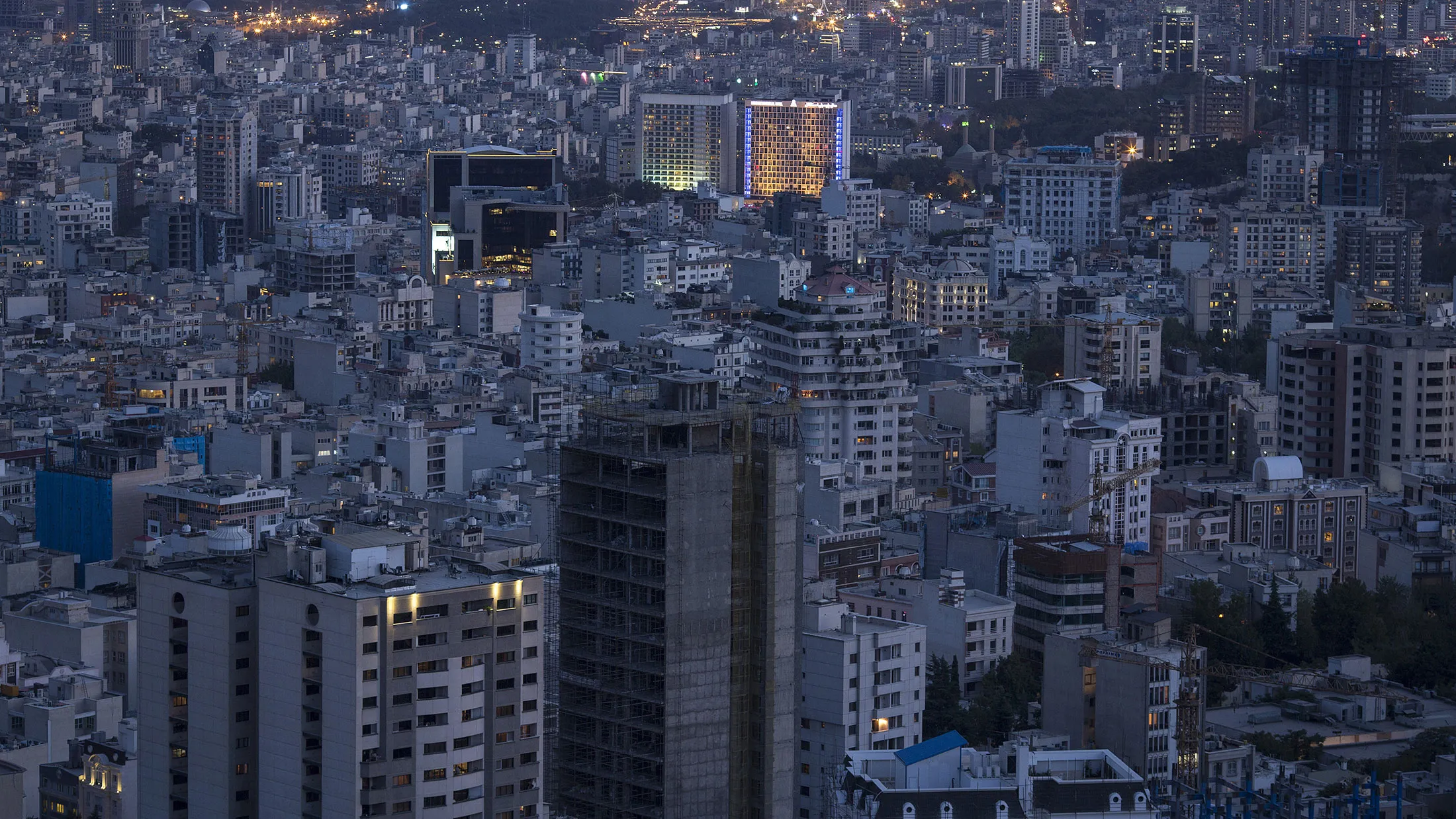 Residential and commercial properties sit illuminated at night on the city skyline in Tehran, Iran.
