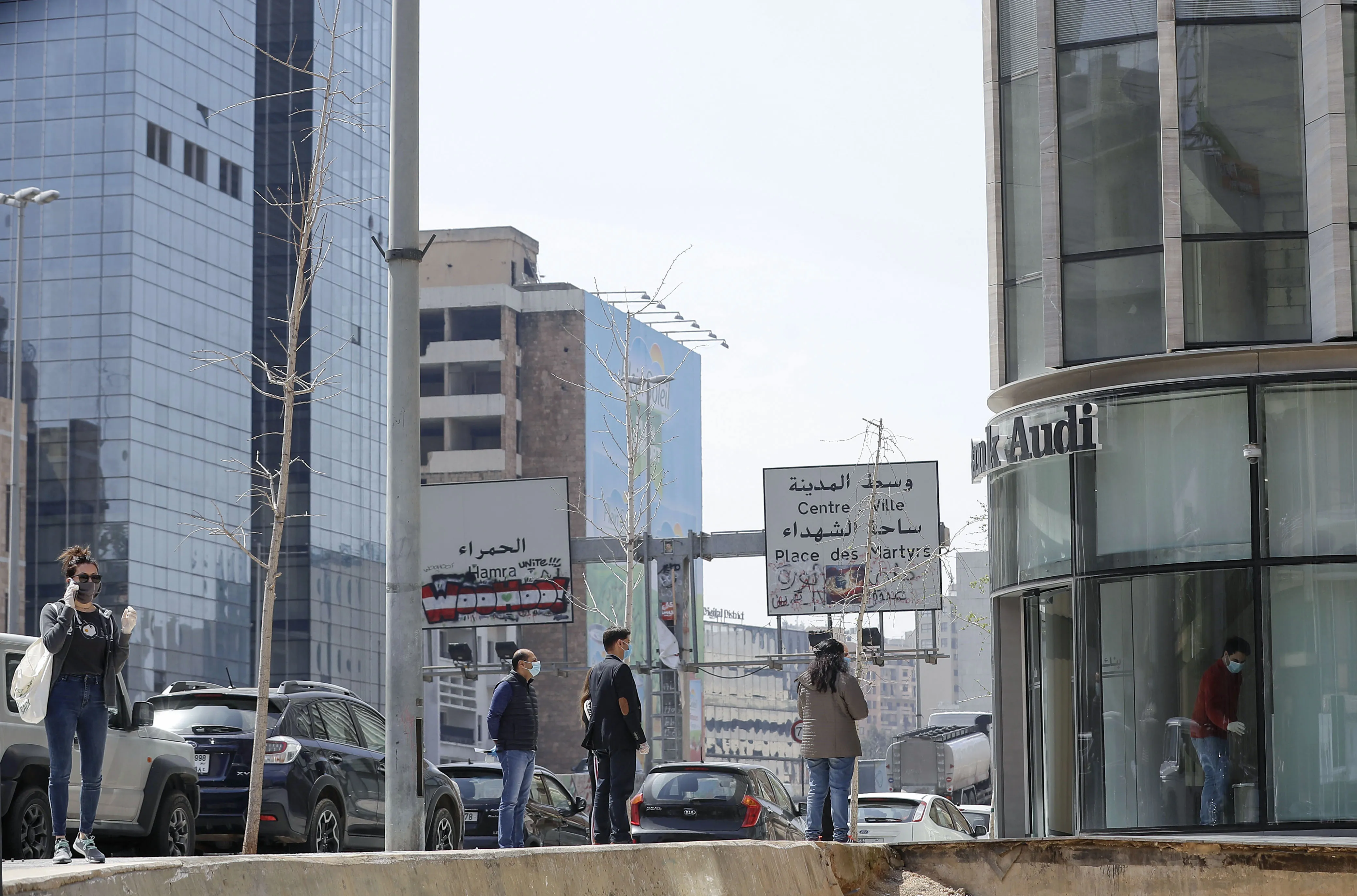 People wearing protective masks&nbsp;queue outside a bank as they wait to withdraw money from an ATM machine in Beirut.