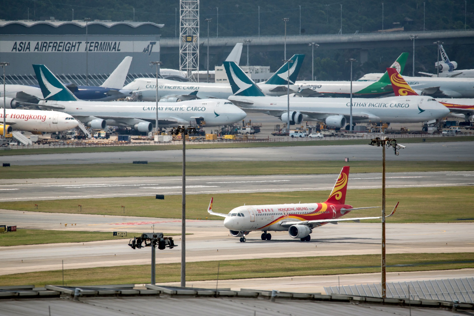 A Hong Kong Express Airways plane&nbsp;taxis past Cathay Pacific Airways Ltd. cargo aircraft at Hong Kong International Airport.
