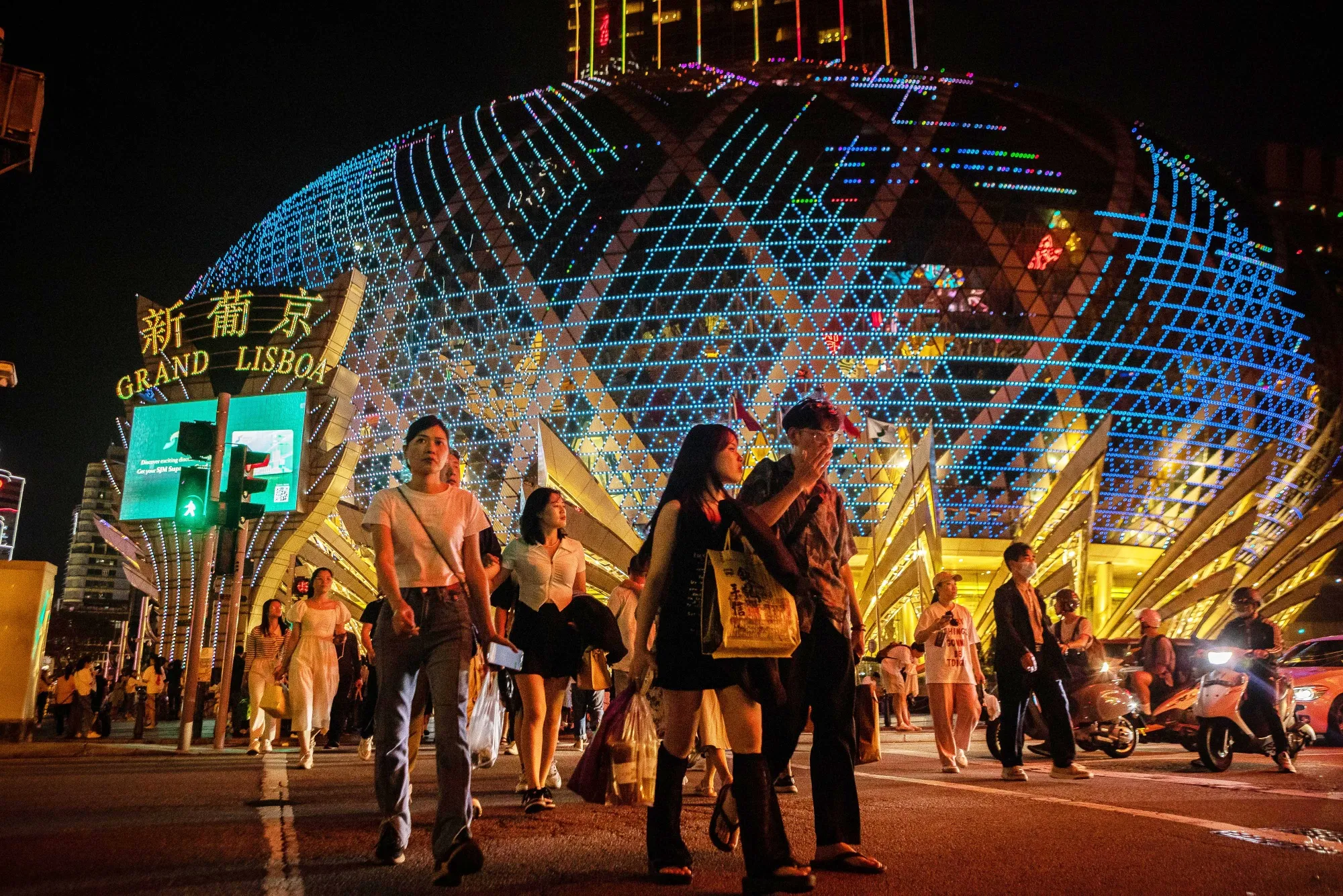 Visitors cross the street in front of the Grand Lisboa casino resort in Macau.