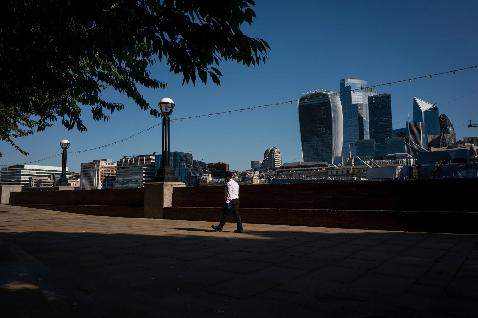 A pedestrian walks in view of skyscrapers&nbsp;in London, U.K., on&nbsp;July 31, 2020.