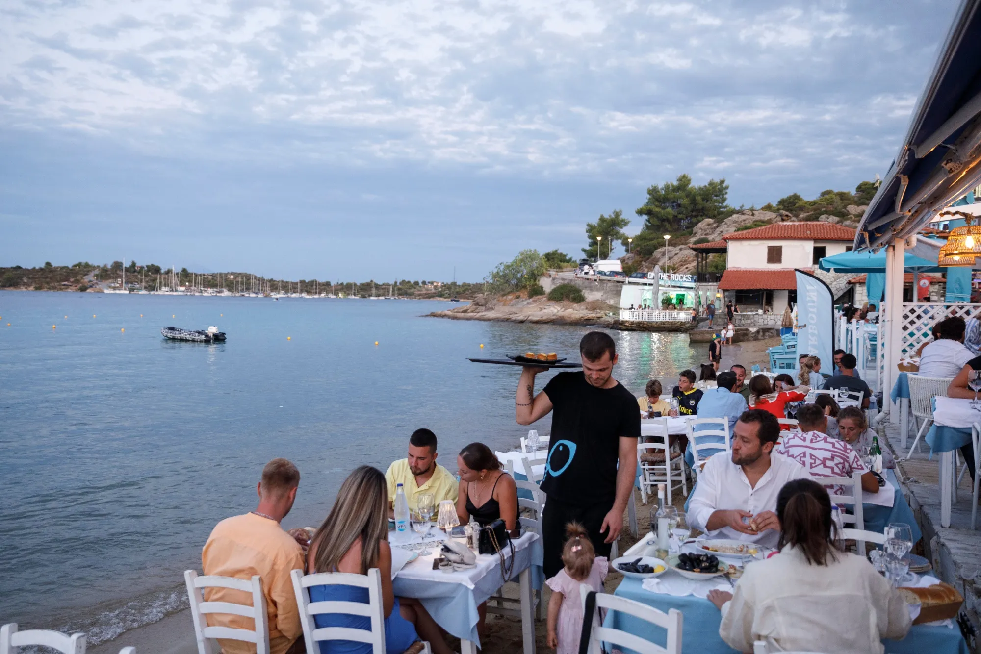 A waiter serves customers at a restaurant by the sea in Halkidiki, Greece.
