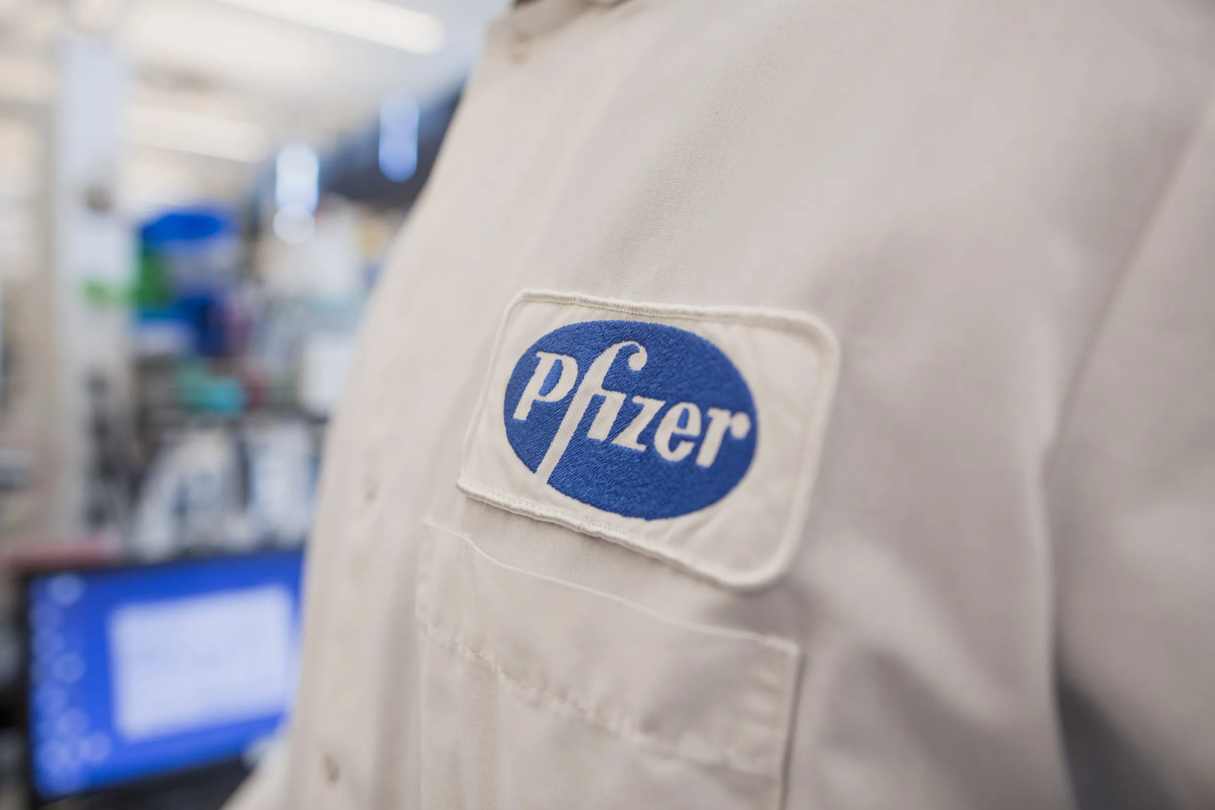 The Pfizer Inc. logo is seen on the lab coat of an employee at the company's research and development facility in Cambridge, Massachusetts, U.S., on Monday, Oct. 26, 2015. Pfizer is expected to report quarterly earnings on October 27.