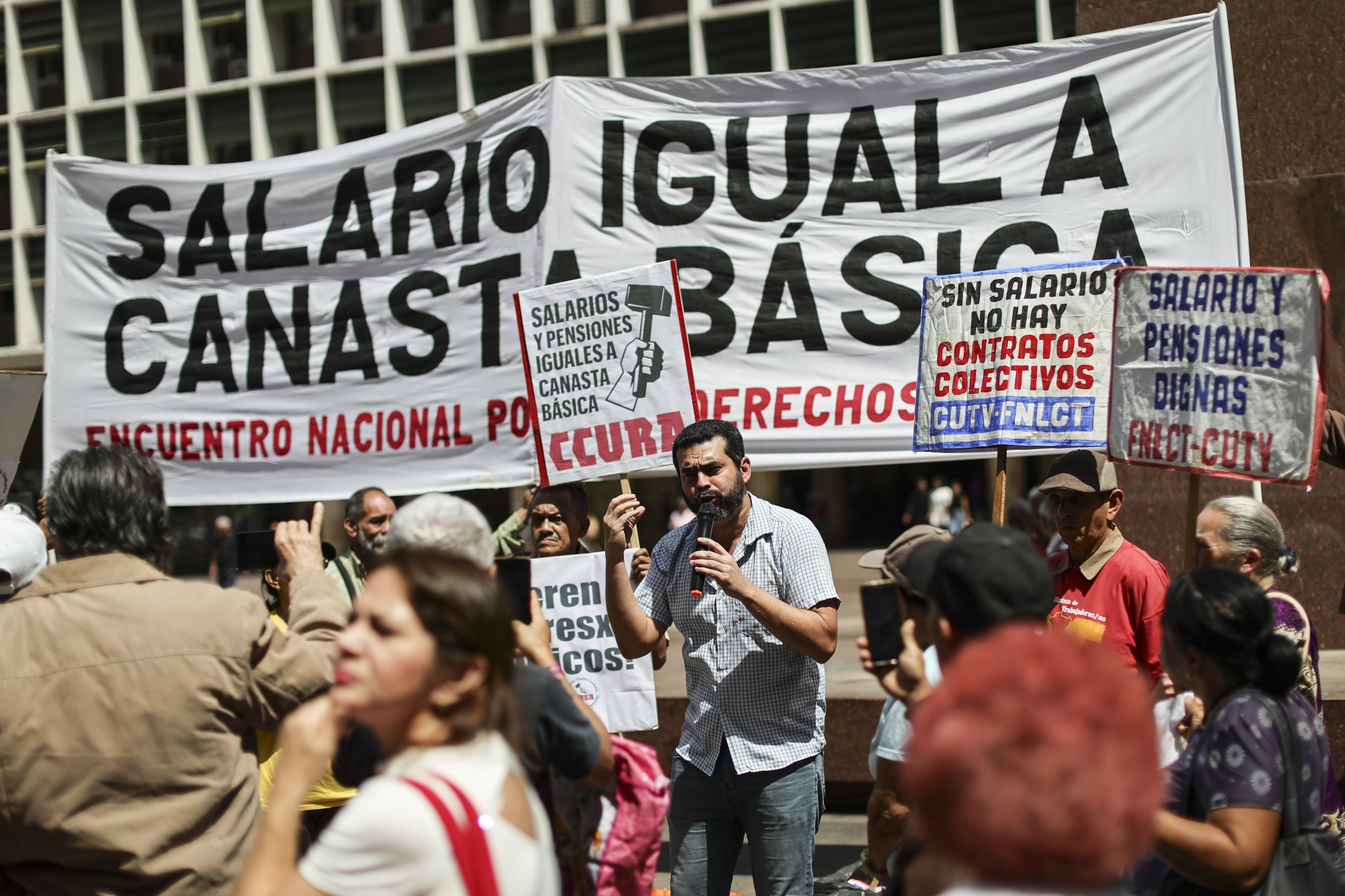 Workers and retirees participate with posters and slogans during a protest for higher wages outside the Labor Ministry in Caracas, on Feb. 26.