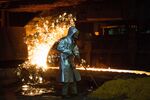 An employee wears protective clothing beside a blast furnace cast house at ThyssenKrupp AG's steel plant in Duisburg, Germany.
