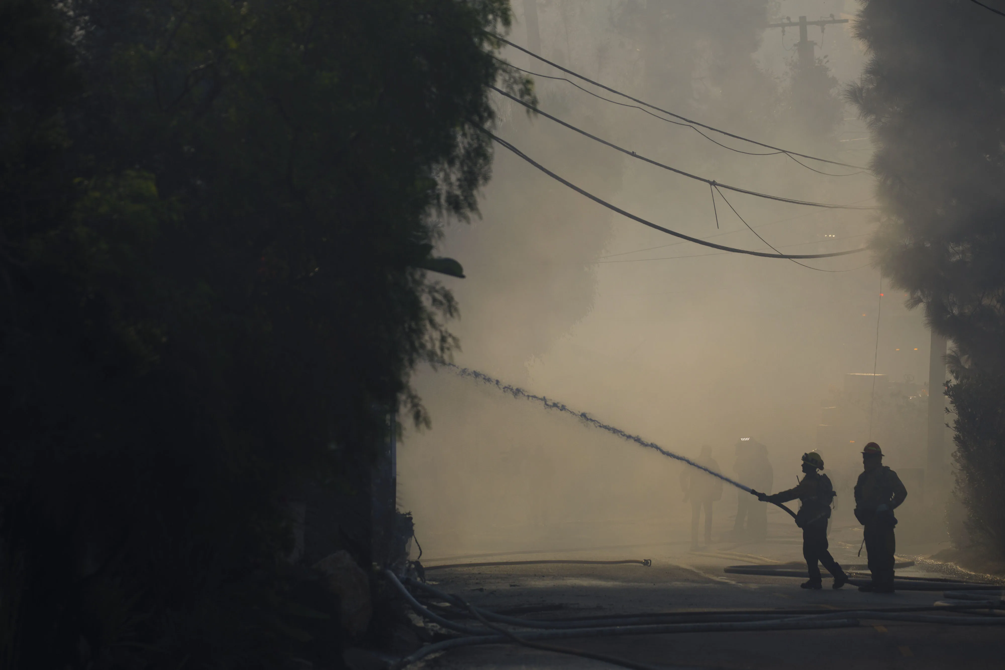 Firefighters spray water on a home damaged during a brush fire in Los Angeles on Oct. 28, 2019.&nbsp;
