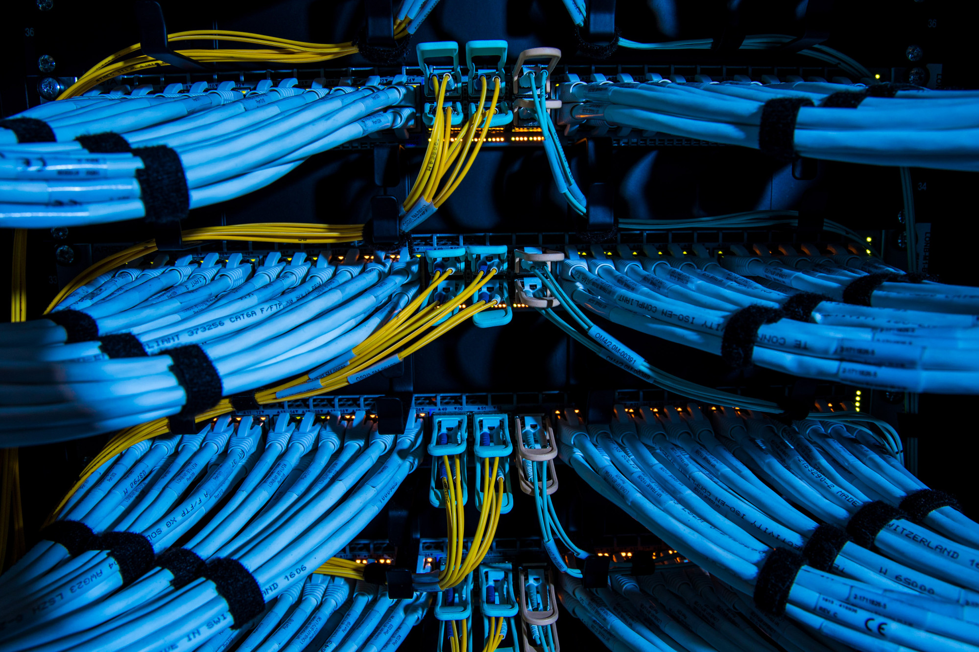 Fiber optic cables, center, and copper Ethernet cables feed into switches inside a communications room at an office in London, U.K.