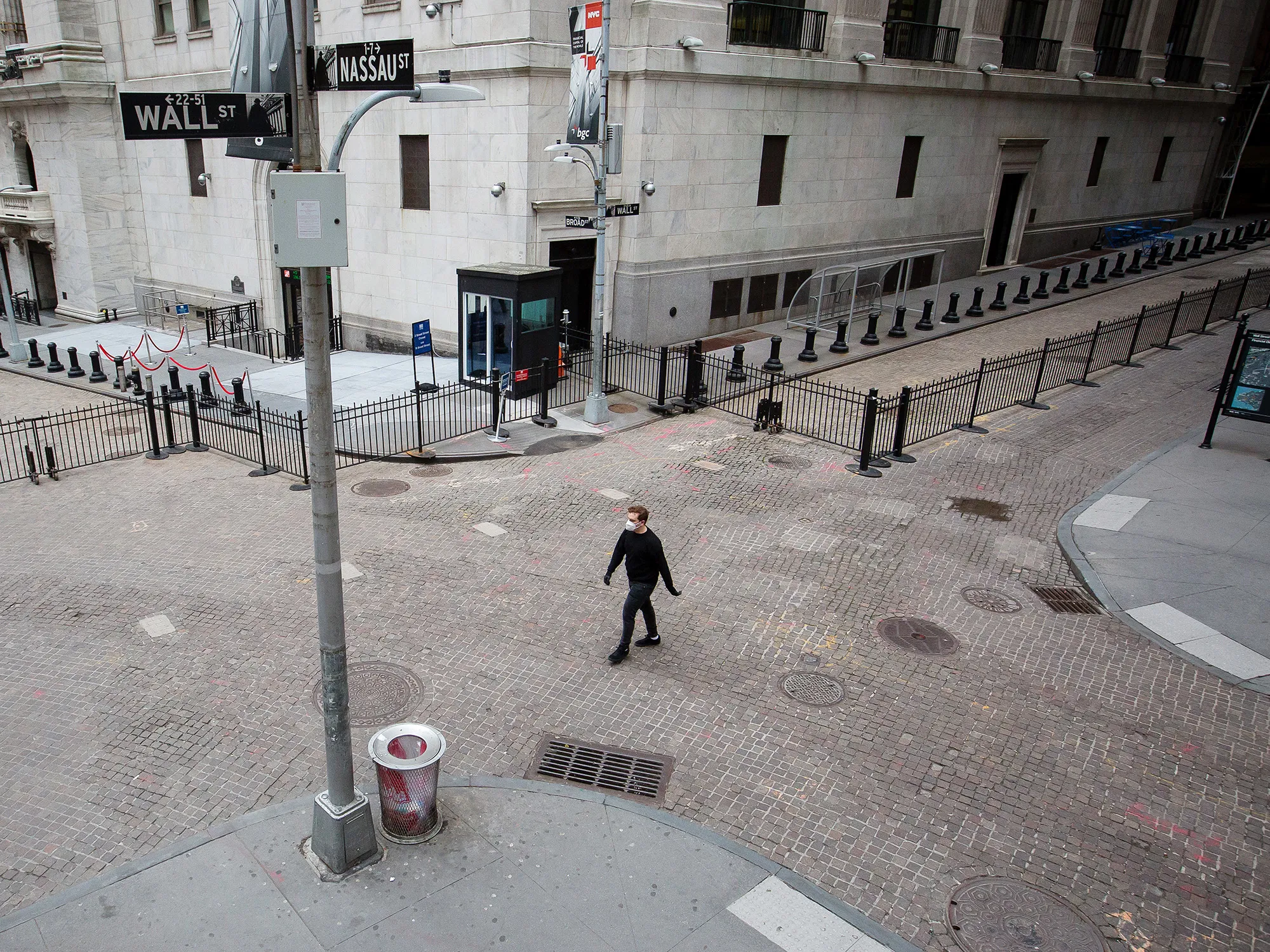 A pedestrian wearing a protective mask walks along Wall Street in New York.