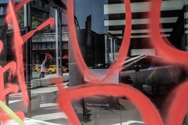 Members of the climate protest group Extinction Rebellion spray paint anti-DOGE messages on the outside of a Tesla showroom on April 22, 2025 in New York City.