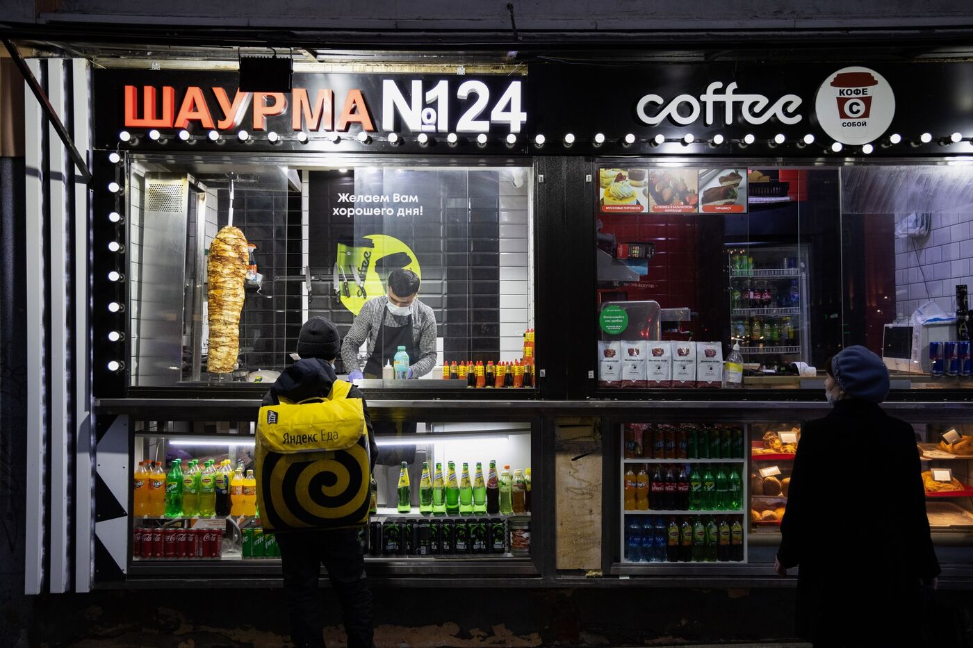 A worker serves a Yandex food delivery courier at a takeaway kebab kiosk in Moscow.