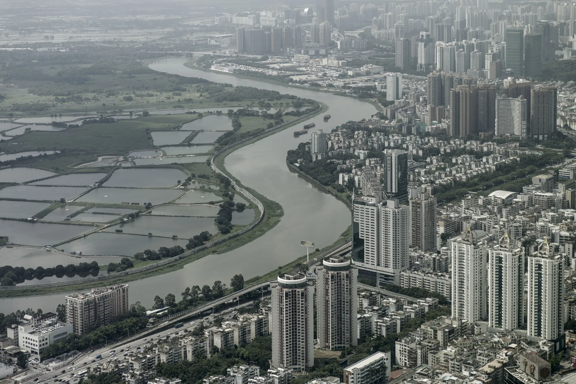 The Sham Chun river marking the border between residential and commercial buildings in mainland China, right, and farmland in Hong Kong.