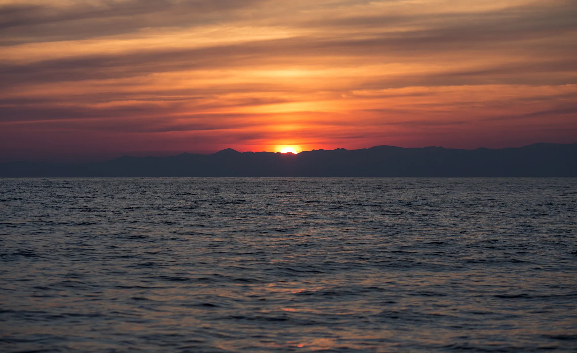 The sun rises over the Turkish coastline in the Aegean sea between Turkey and Greece.