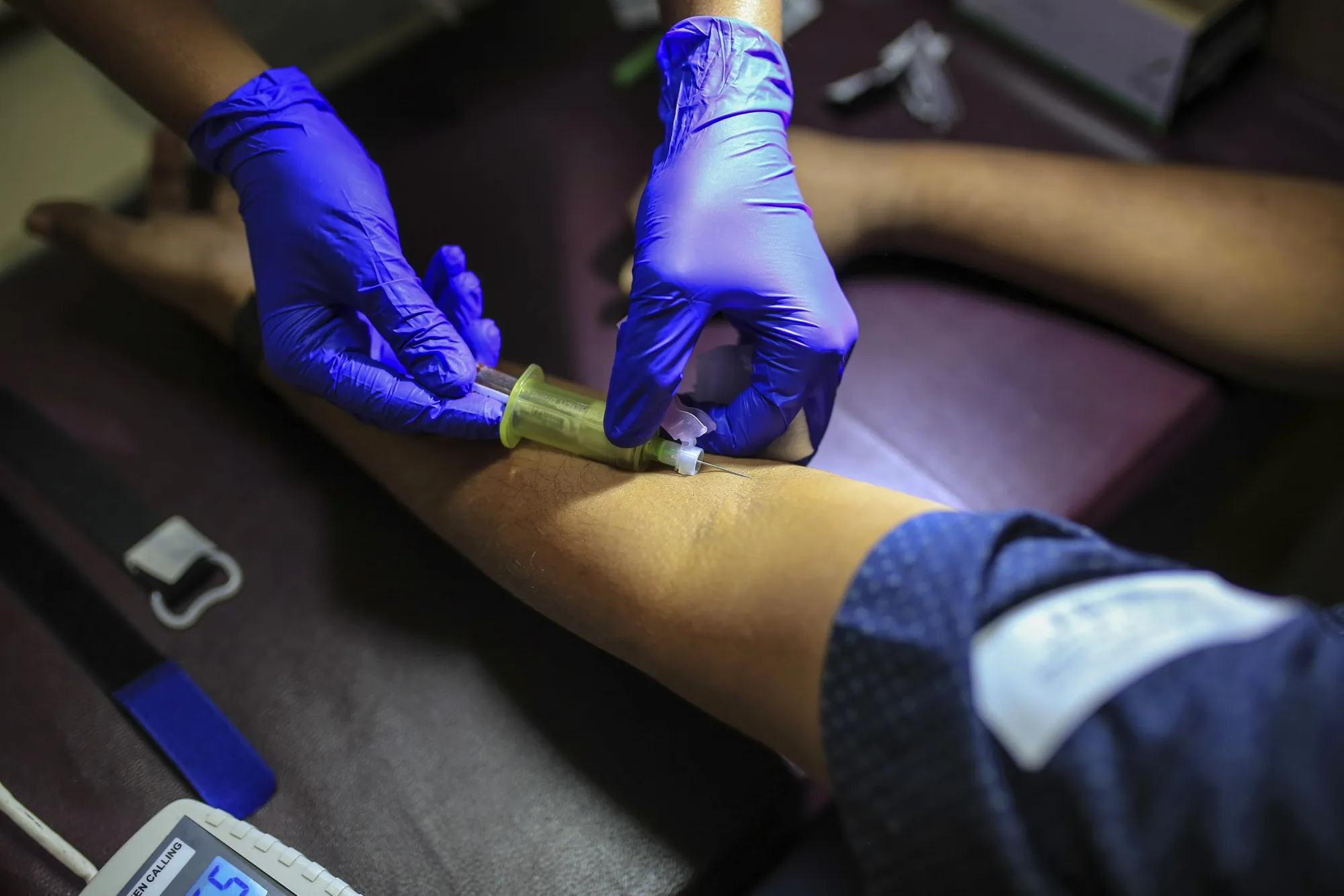 A nurse takes a patient's blood sample in a pathology lab.