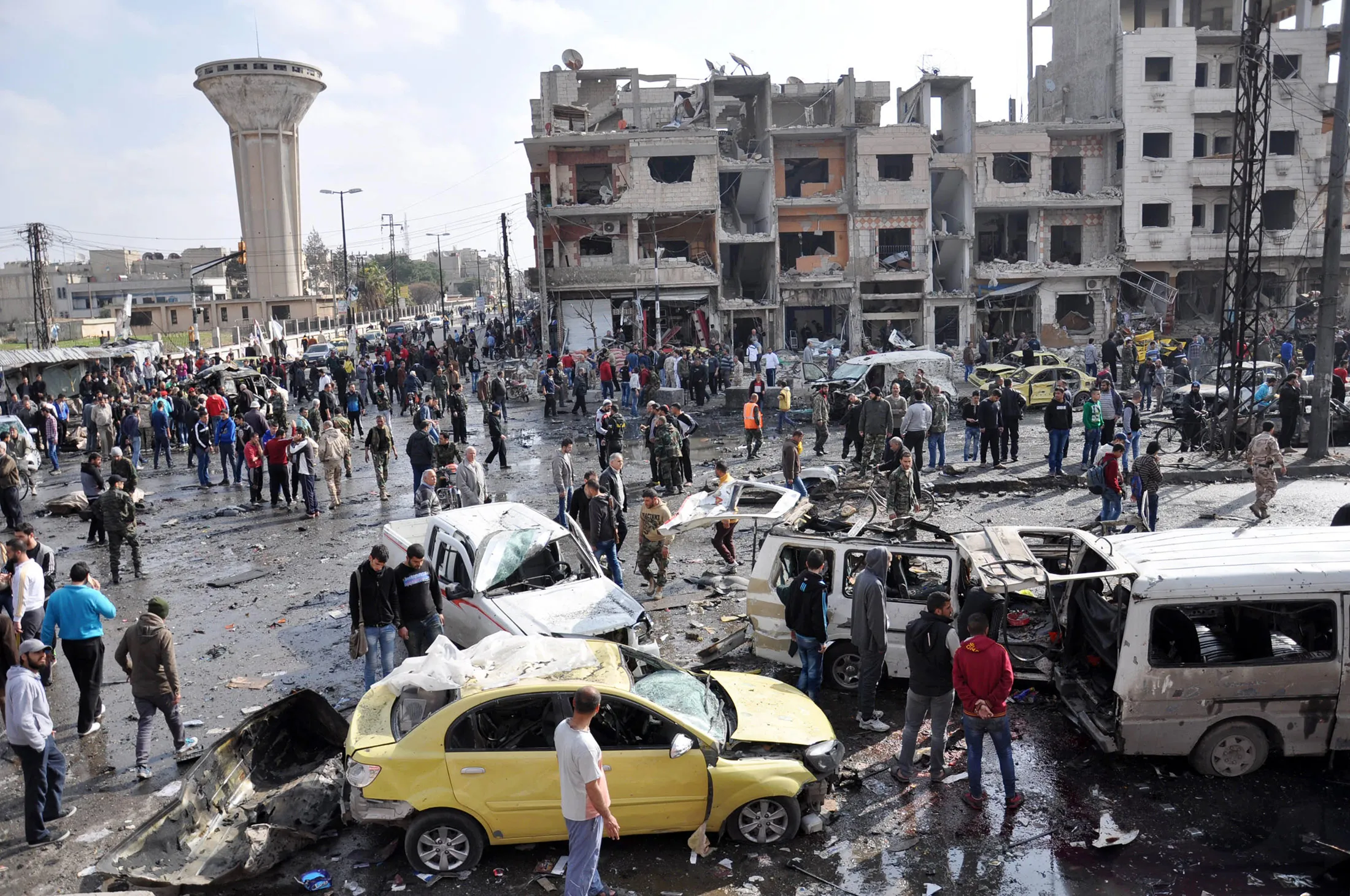 Syrians gather at the site of a double car bomb attack in the Al-Zahraa neighbourhood of the central Syrian city of Homs on February 21, 2016.
