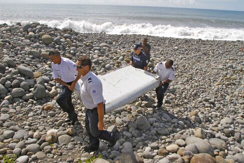 French police officers carry a piece of debris from a plane on Reunion Island, on July 29, 2015. Photographer: Lucas Marie/AP Photo