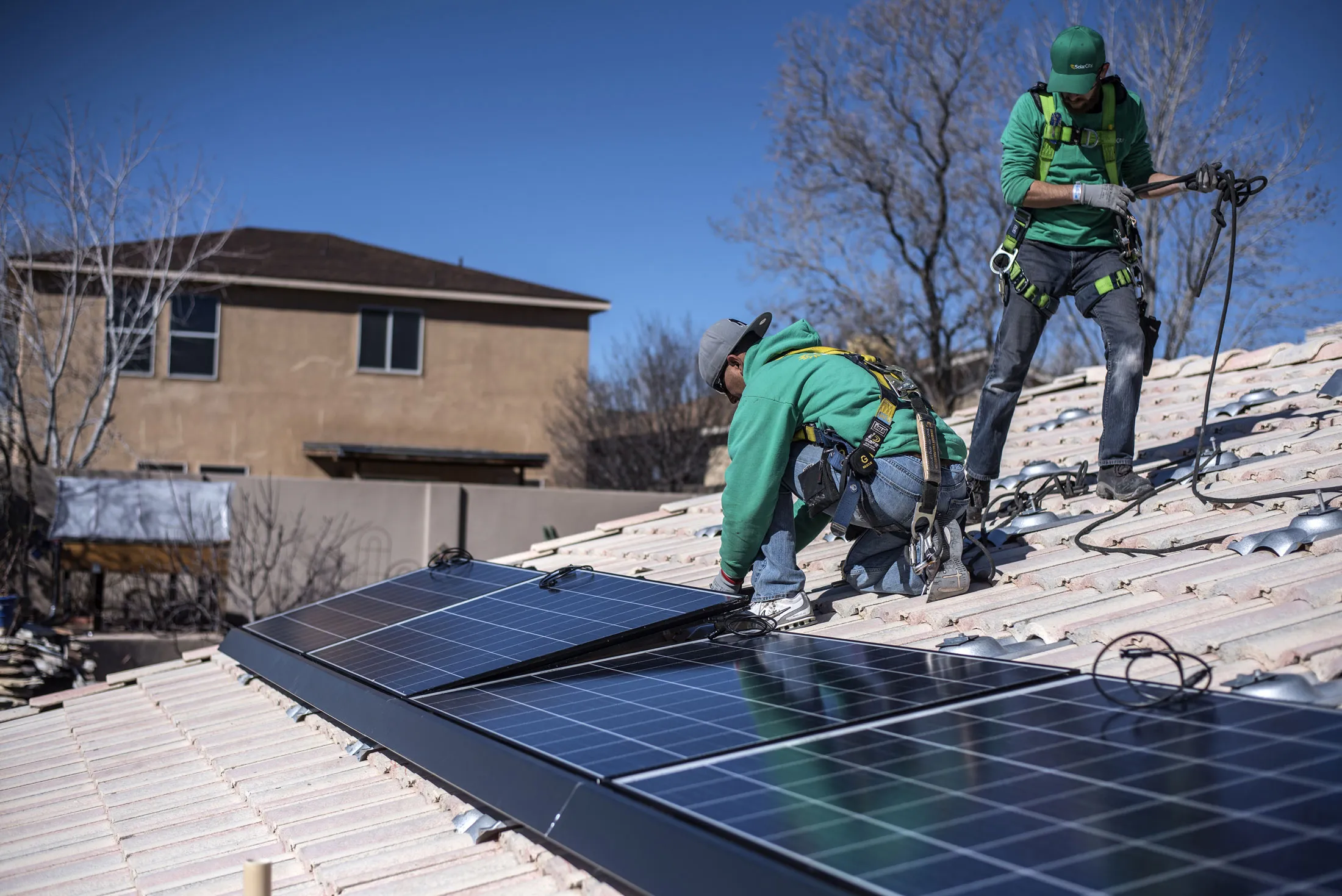 A worker secures a solar panel to a residence’s rooftop during a SolarCity installation in Albuquerque.
