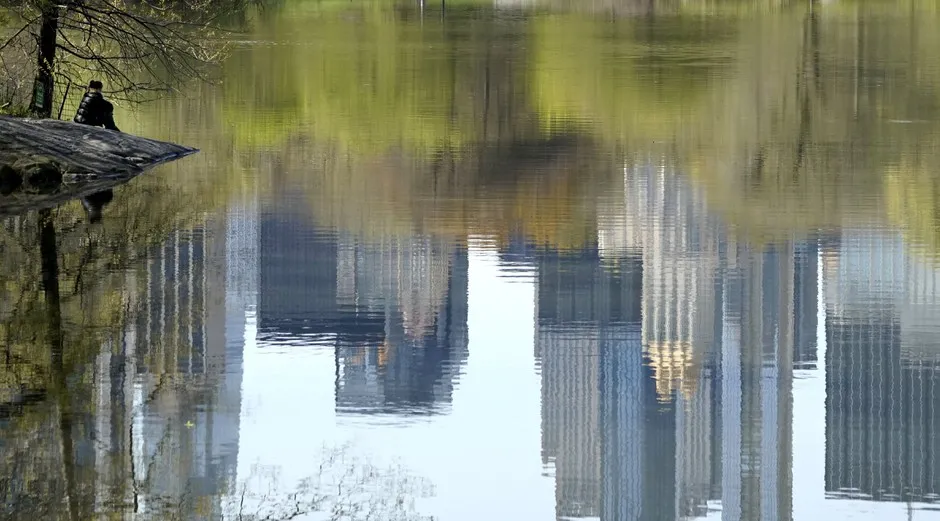 The Manhattan skyline is reflected in a lake in New York City's Central Park