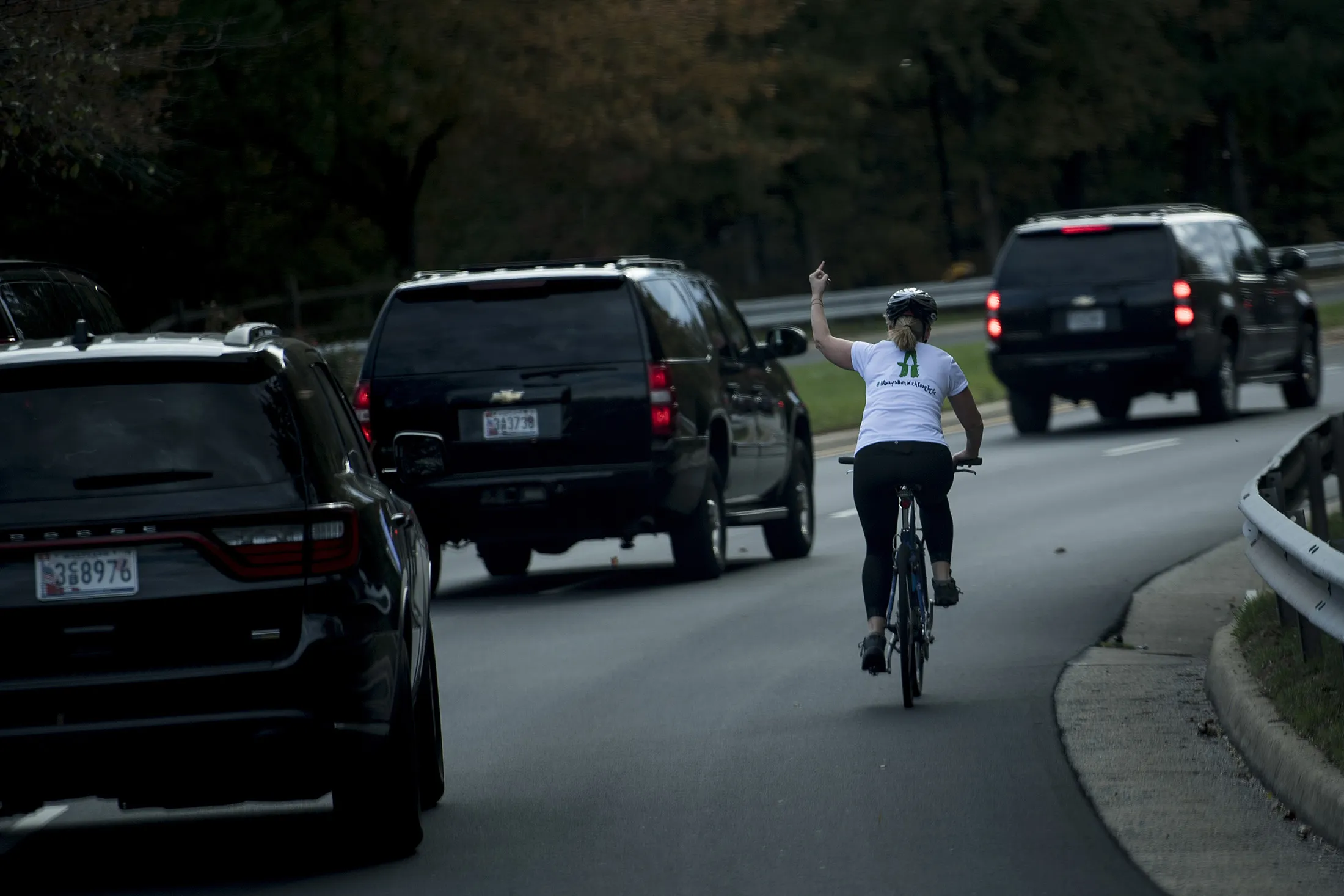 A woman on a bike gestures with her middle finger as Trump’s&nbsp;motorcade departs Trump National Golf Course in Sterling, Virginia, on Oct.&nbsp;28, 2017.