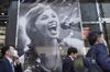 Pedestrians wearing protective face masks walk past an advertisement for a karaoke store, temporary closed due to the coronavirus outbreak, in Ginza shopping district in Tokyo, Japan, on April 8, 2020. 