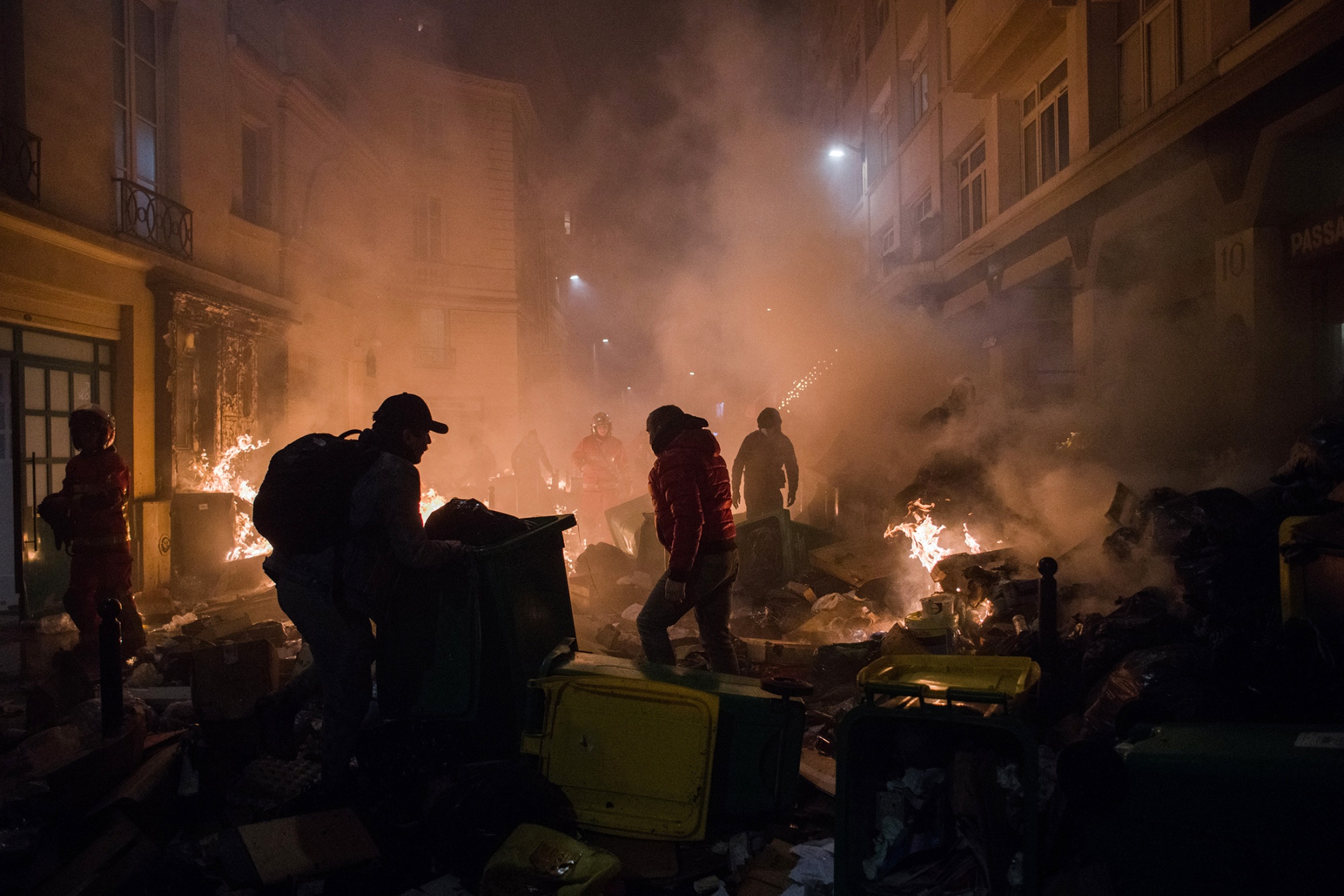 Residents and firefighters try to extinguish a street fire on Thursday during protests in central Paris over Emmanuel Macron’s pension reform plan.