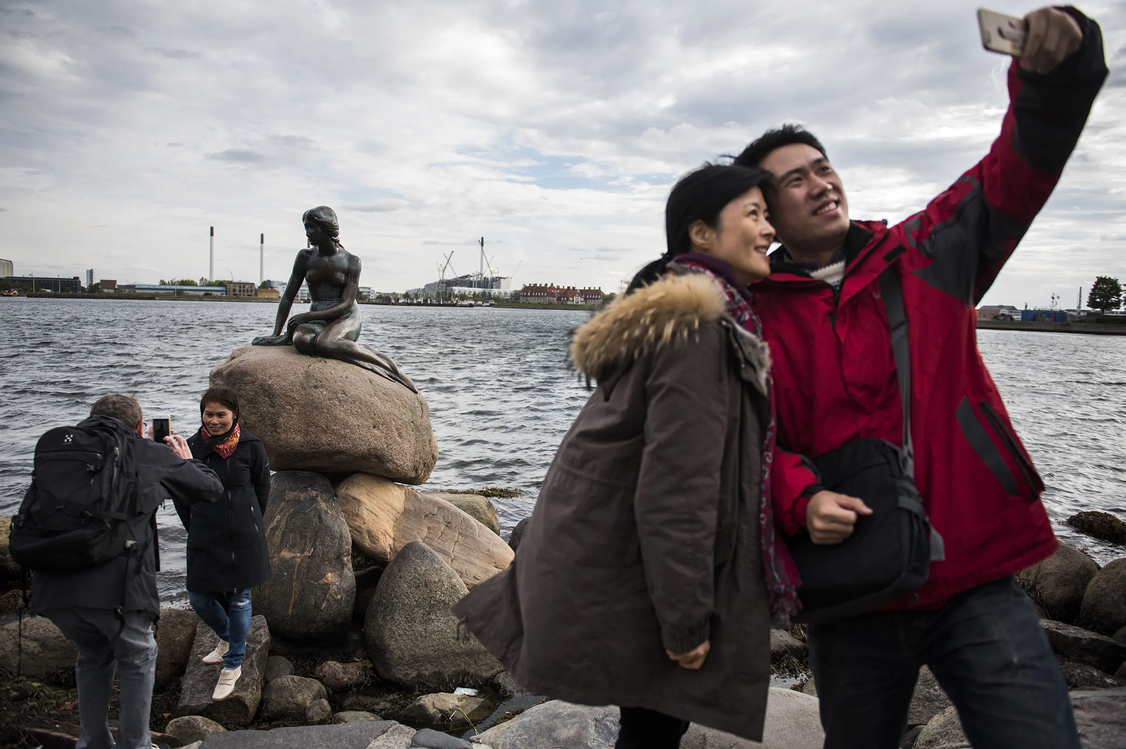 Tourists photograph themselves with the bronze statue "The Little Mermaid" at the harbour in Copenhagen.