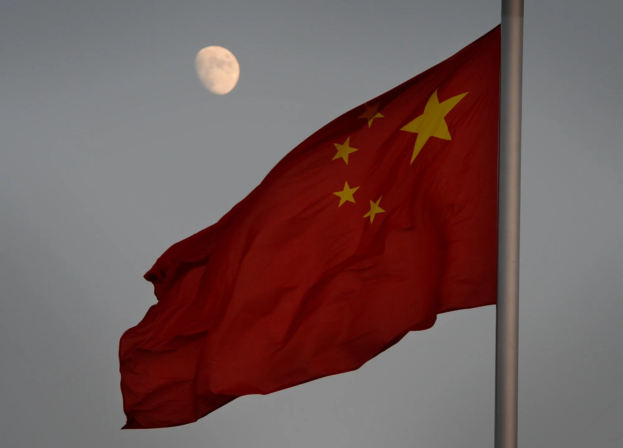 The Chinese flag is seen in front of a view of the moon at Tiananmen Square in Beijing.