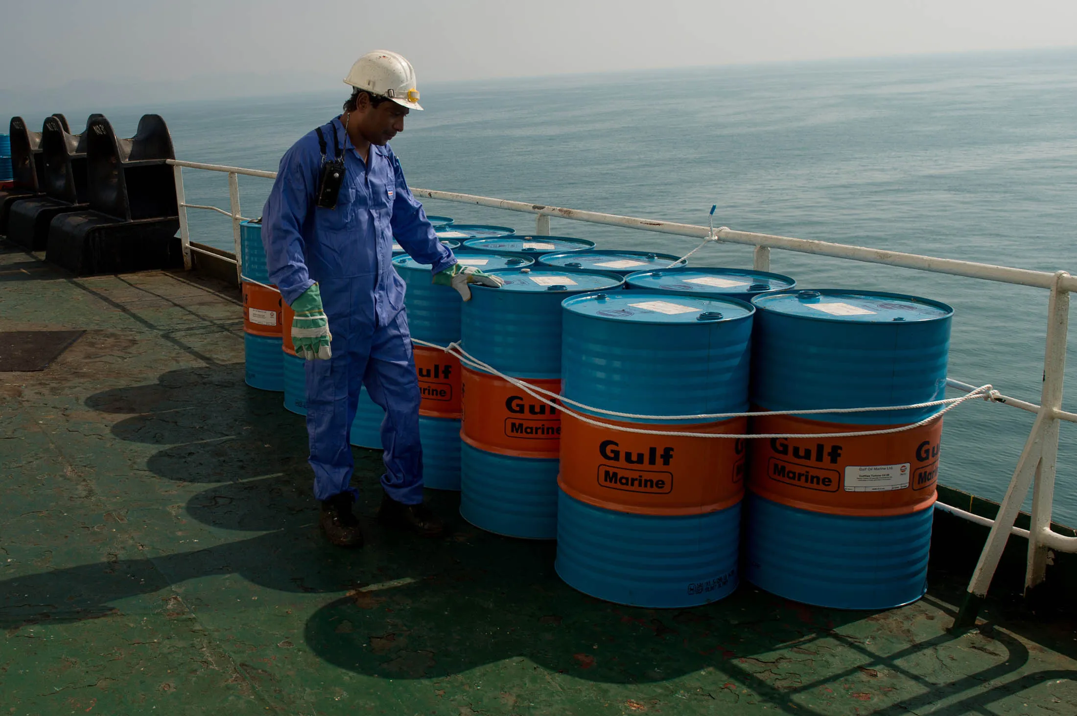 A crew man secures Gulf Marine oil drums on the deck of oil tanker 'Devon' as it prepares to transport crude oil from Kharq Island to India in Bandar Abbas, Iran, on Friday, March 23, 2018. Geopolitical risk is creeping back into the crude oil market.