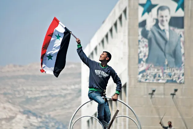 Hoisting the flag for Assad at a pro-government rally in March