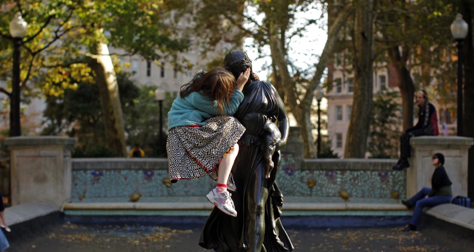 A bonding moment: A girl sits in the arms of a statue in Rittenhouse Square in Philadelphia.