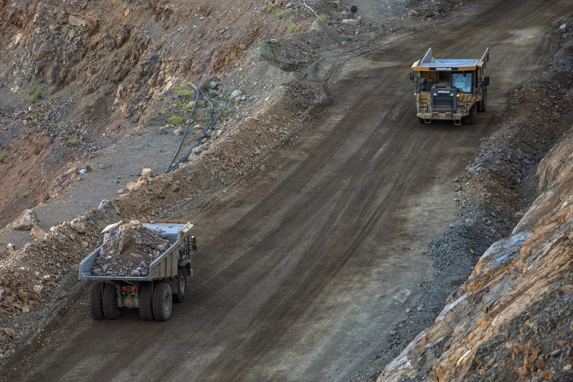 Dump trucks move raw ore inside the pit at a mine&nbsp;in Mountain Pass, California.