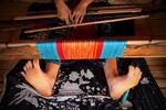 A Baduy tribeswoman weaves at home.